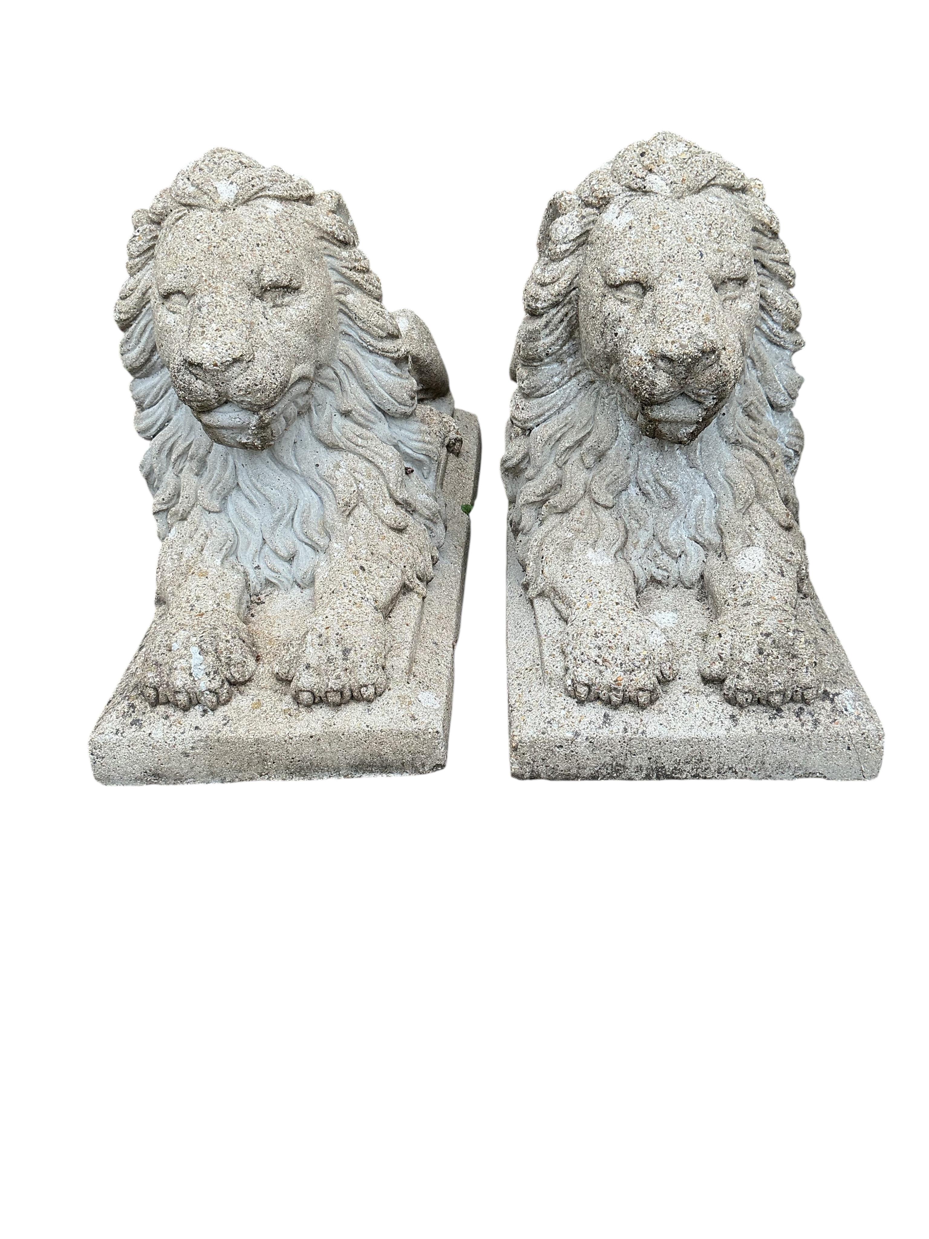 A pair of reconstituted stone lion garden ornaments, length 81cm, height 50cm